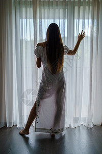 后退身着白色透明衣服的年轻女子双影带背面观视从窗帘的房间走过户后脸朝边望去漂亮的看图片
