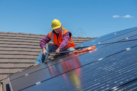 安全在屋顶上打扫太阳能电池板的青年工人关注面板橙图片