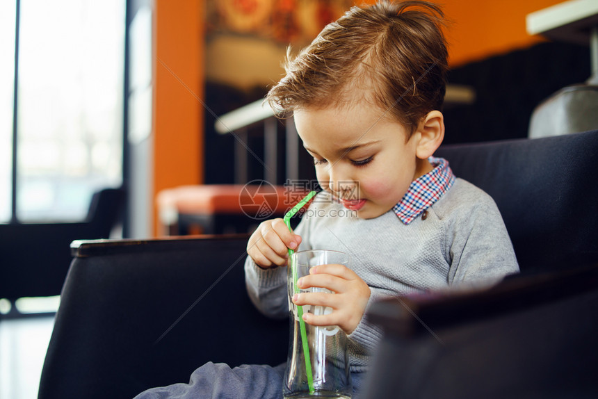 坐在咖啡馆或家中的椅子上拿着空杯用吸管检查看坐着椅子的儿童长着三年幼小的外表健康一种学步的儿童图片