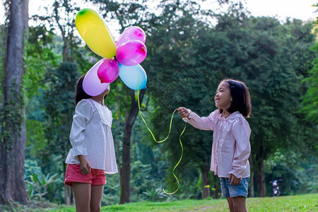绿色两名女孩在公园户外的内持有多彩玩具气球自由阳光图片