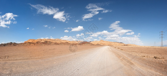 沙丘漠中通往遥远岩石的路面远足图片
