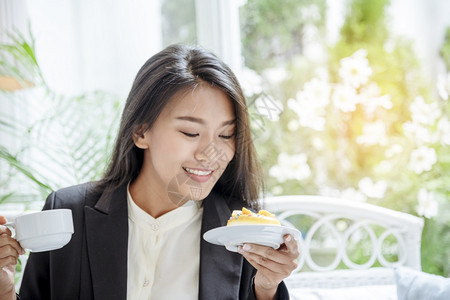 咖啡店晴天妇女在办公室工作后在咖啡厅喝着温暖的口味时拿着咖啡杯放松享受愉快时光紧握坐在办公桌边拿着甜咖啡杯放松和欢乐时光的女士们图片