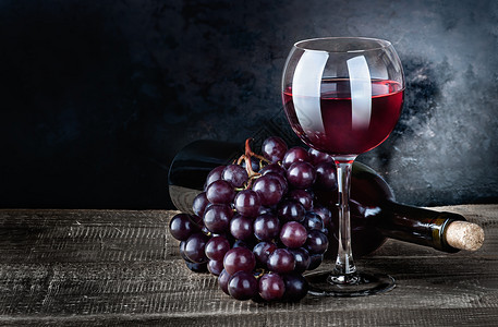红酒葡萄和瓶子放在木制桌上酒瓶在黑底幕下葡萄和瓶装干燥优质的老图片