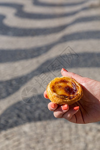 一顿饭休息甜点在葡萄牙里斯本的背景点上葡萄牙传统妇女手中的Pasteisdenataspathes图片
