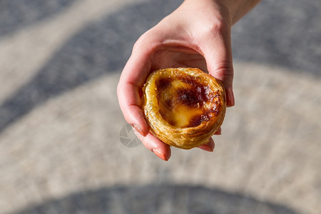 旅行在葡萄牙里斯本的背景点上葡萄牙传统妇女手中的Pasteisdenataspathesnata蛋糕典型的图片