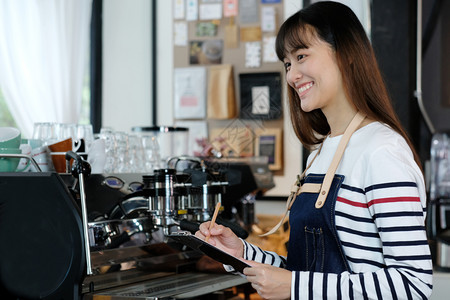 女围裙在咖啡厅柜台用微笑的面容食物和饮料商业概念做笔记点菜餐饮生意肖像图片