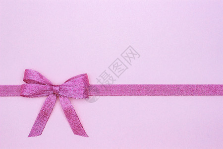 装饰上闪亮的彩带弓紧贴在粉色面糊背景上复制文字空间顶视图布局上闪亮的彩礼带和粉色背景上的弓多于周年纪念日图片