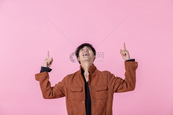 一个英俊的亚洲男子英俊的年轻男子用两手和指对着侧眼看在爱中孤立的相机在粉红色空白复制间室背景男人眼睛支线图片
