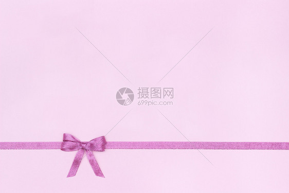 装饰上闪亮的彩带在粉色糊面背景上弓下并复制文字空间顶视图布局上闪亮的彩礼带和粉色背景上的弓水平问候图片