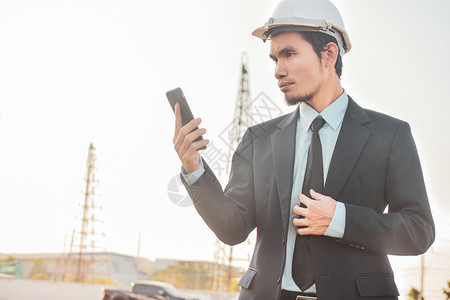 头盔地点建筑工的商人打电话手机或移动智能电话在施工地移动的图片