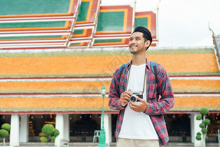 成人讲话亚洲男游客在夏季时泰国曼谷的WatSuthatThepwararamRatchaworawihan步行谈论智能手机和微笑图片