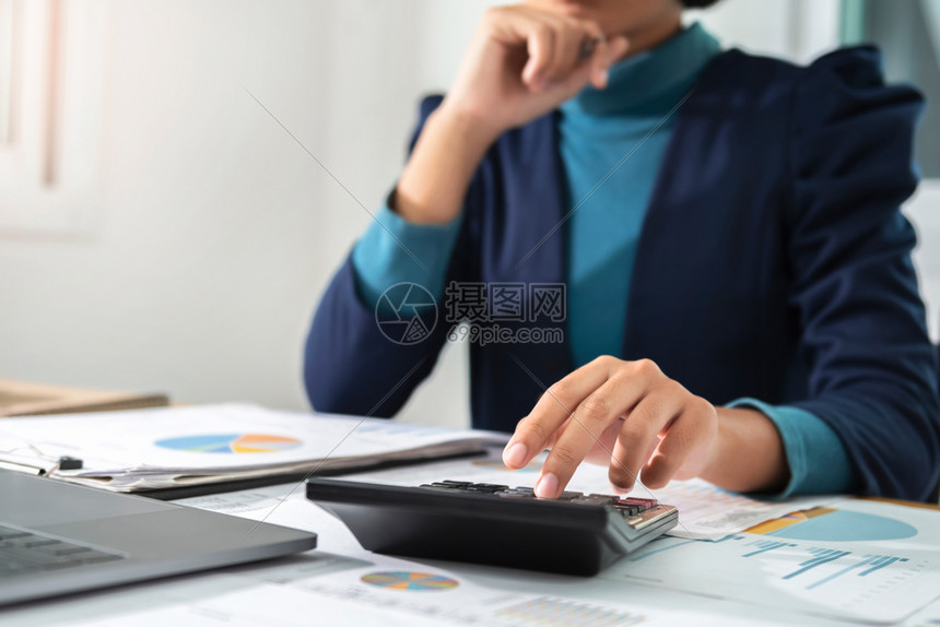 在办公室概念财务和会计方面使用算器和膝上型机工作的商业妇女文书工作笔桌子图片