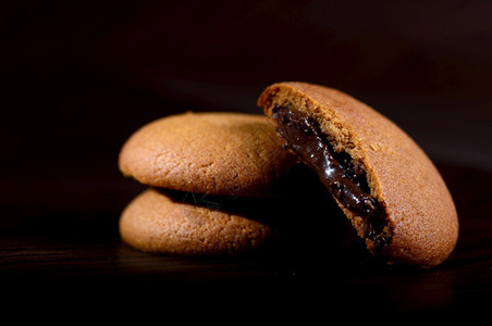 新鲜的酥脆甜巧克力奶油饼干棕色巧克力黑色背景奶油馅图片