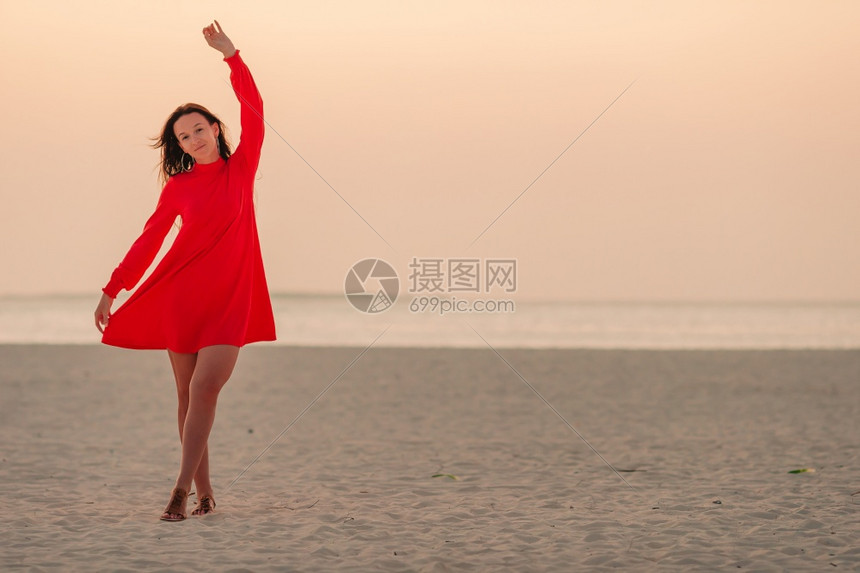 请享用海滨夕阳下白沙滩上的美丽女人夕阳下白沙滩上可爱快乐的小女孩红色图片