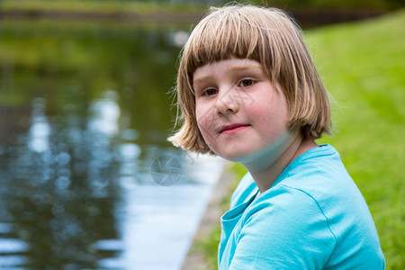 湖童年坐在公园池塘水边的金发女孩户外图片