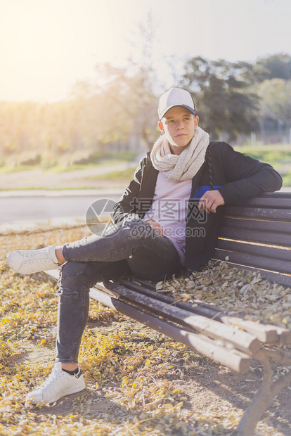背包孤独时尚的青少年坐在木板凳上市街临时工穿着快乐的图片