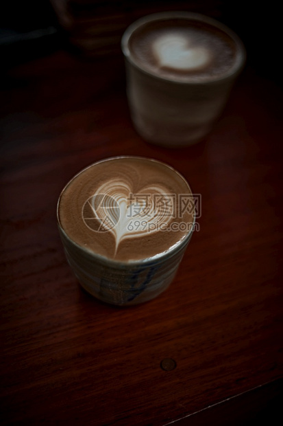 咖啡店以白泡沫热拿铁艺术咖啡为焦点在木制桌上有选择地集中杯热拿铁艺术咖啡重点是白泡沫热拿铁艺术咖啡早餐可选择的图片