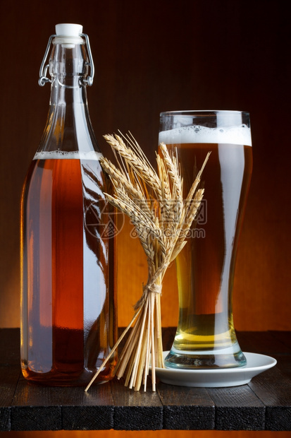 白色的贮藏啤酒未装瓶的和杯子小麦在木制桌上图片