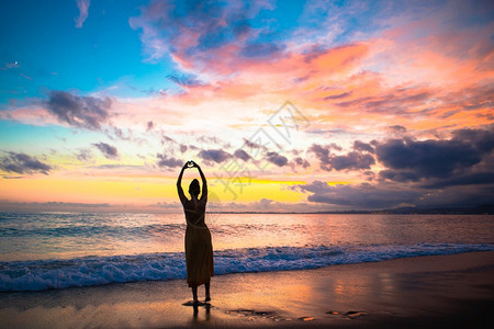 假期闲暇海滩上的女人享受暑假看着海日落时在沙滩上的年轻女士们日光浴图片