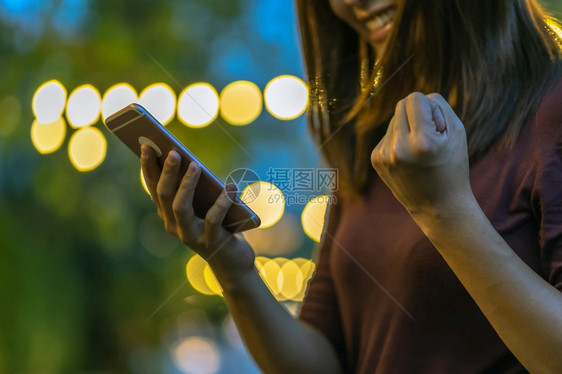 使用智能手机的亚洲女在户外公园庆祝商业和生活方式概念的贴近亲手快乐的玩曼谷图片