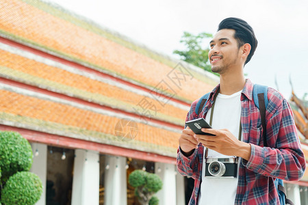 英俊的笏在泰国曼谷ThepwarararamRatchaworawihanSolo旅行和背包机概念上游街寻找智能手机旅游图片