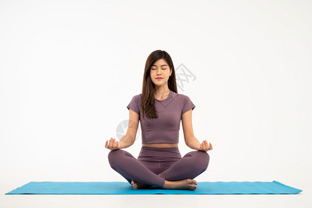 微笑幸福亚洲运动和健康的青年妇女在白种背景下孤立的瑜伽垫上做练习和冥想健康生活的概念正在做图片