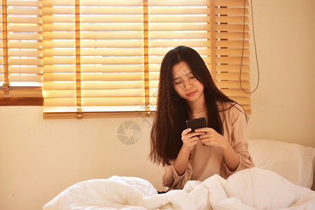 聪明的使用移动智能手机的妇女是离子卧室愉快女孩图片
