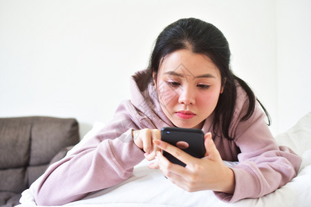 无线的使用移动智能手机的妇女是离子卧室愉快图片