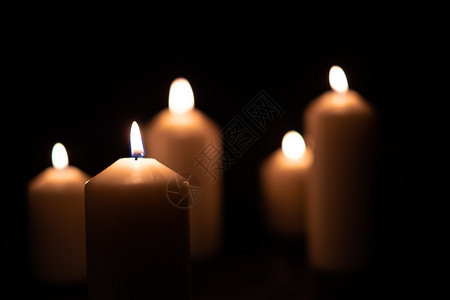 火焰辉光热的5支火蜡烛在黑色背景上闪亮燃烧图片