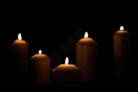 辉光黑暗的放5支火蜡烛在黑色背景上闪亮燃烧图片