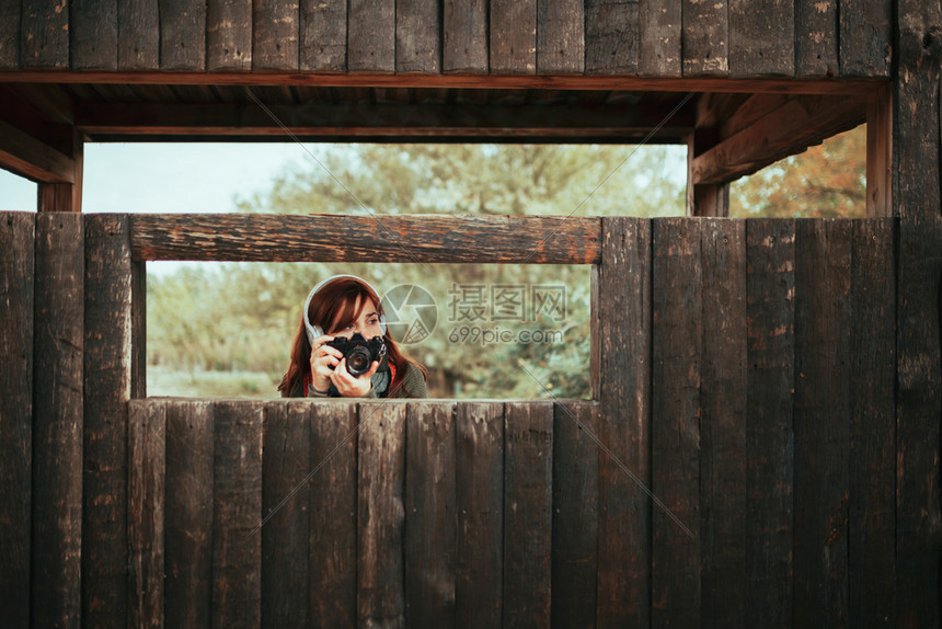 年轻女子在森林中木屋拍摄照片落下服用随意的图片