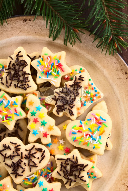形式巧克力为圣诞节自制的烤糖饼干上面有冰霜和多彩的喷洒放在蛋黄酱板上拍下相片在边刨冰图片