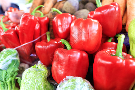 乡村的有机收成大熟红甜椒特写在其他蔬菜的背景上在白天市场上的托盘出售市场的其他蔬菜背景上的大红甜椒图片