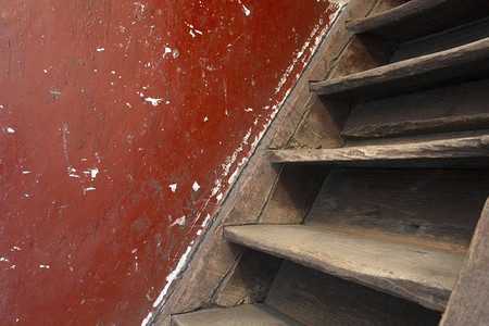 内部的旧损坏棕色木楼梯和通往阁的红墙需要翻新特写旧损坏的棕色木楼梯和通往阁的红墙需要翻新古老的红色图片