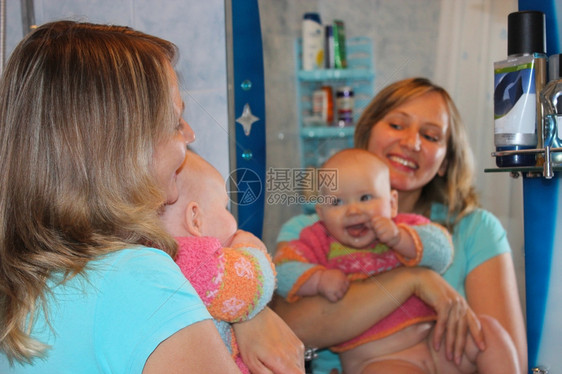生活快乐的母亲与她女儿在镜子里反射着自己的小女儿玻璃化妆品图片