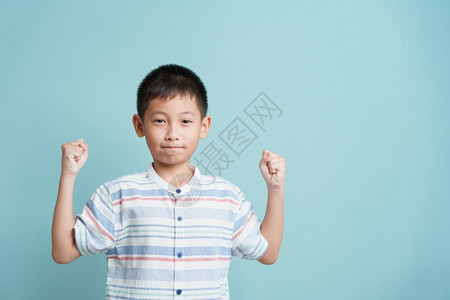 亚洲快乐的小男孩站在蓝色背景的亚洲小男孩孤立地站着可爱男人的肖像成功快乐和微笑聪明的喜悦亚洲人图片