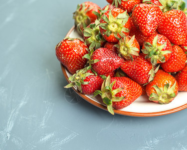 庄稼草莓放在浅蓝色背景的白盘中浅蓝色背景的草莓盘子甜点图片