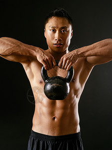 一种照片来自位亚裔男在黑暗背景下以水叮当的铃声进行锻炼成人正面图片