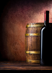 酒红色昂贵的一瓶酒和桶装在布贡迪背景上瓶装酒和桶在布贡迪上瓶子图片