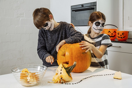 男生假期颅骨两个小孩头脸涂面粉在厨房里切南瓜图片