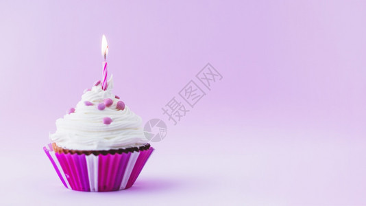 刨冰黄色的周年纪念日生蛋糕有照亮蜡烛的紫色背景图片