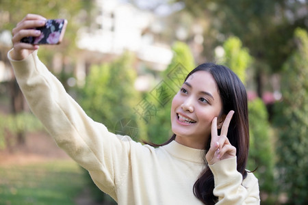 游客移动的年轻笑着亚洲妇女正在拍照和自图片