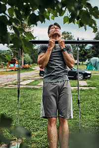 关心夏天年轻人在暑假期间露营时进行体操锻炼在引向上单杠做引体向竞技图片