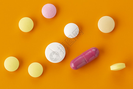 橙色背景下各种各样的胶囊药物图片