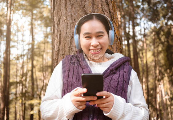 在园艺技术和放松概念中亚洲青年妇女听耳机音乐的庭园技术和放松概念请享用经过移动的图片