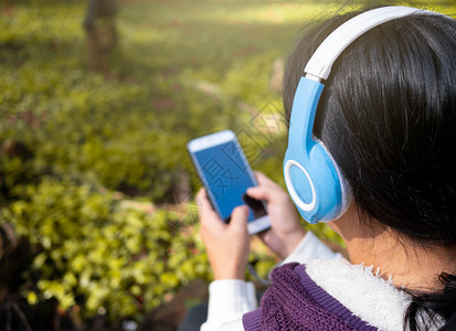 吸引人的年轻在园艺技术和放松概念中亚洲年轻女孩听耳机音乐的亚裔青年女孩请享用图片