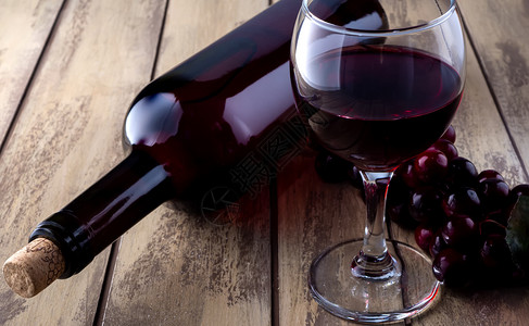 享受饮料装满玻璃和葡萄的酒瓶红杯和葡萄放在旧木板上的酒瓶红杯和葡萄液体图片
