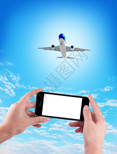 在蓝色背景上使用手机和飞的女手握在蓝色背景上使用手机和飞的女手细胞空气掌上电脑图片
