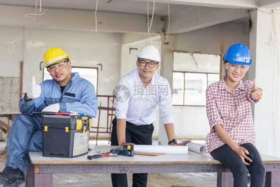 商业建筑工程师团队作安全信托小组负责在建筑工地硬帽子保护主任和土建工程师概念上安装白色黄全硬帽保设备C建筑工程师团队女士商人图片