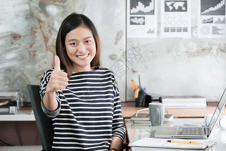 象征年轻的亚洲女商人坐在她的办公桌前室时抽起笑容和微正面的表情商业概念中的精细表述积极专业图片